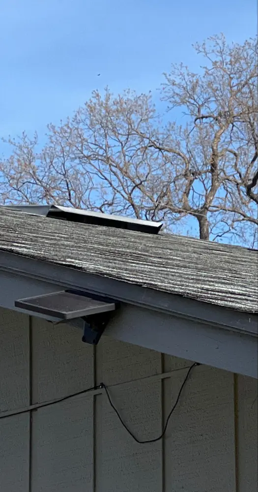 Common low profile off-ridge attic vent installed on an asphalt composite shingle roof. This vent does not feature external baffles that would accumulate debris and embers during a wildfire; however, the screen mesh size is difficult to assess from the ground and is typically greater than 1/8 inch.