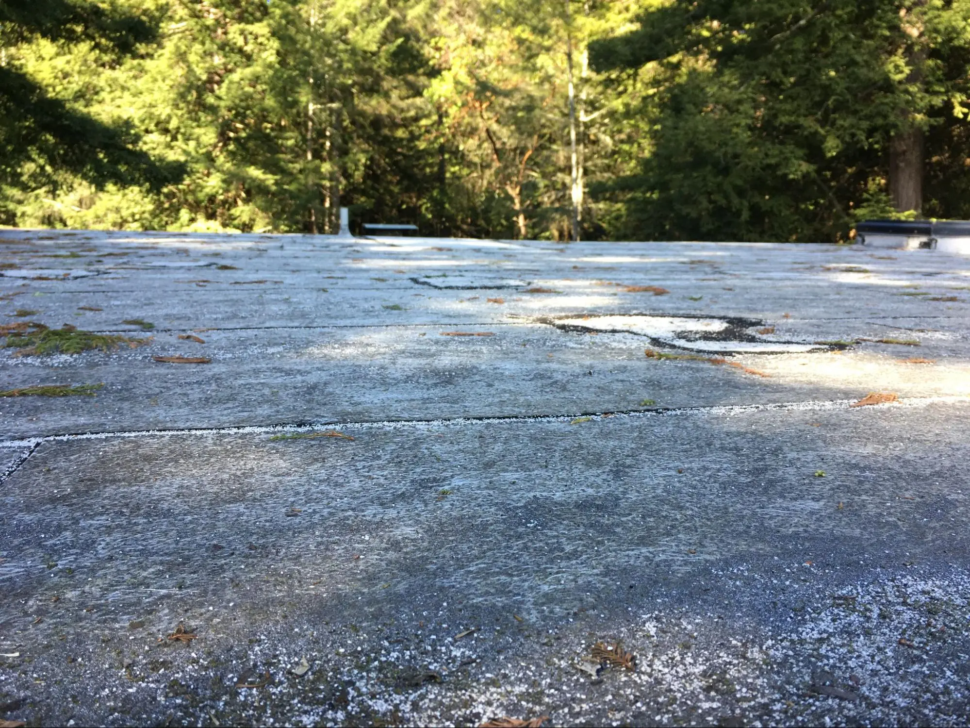 Modified bitumen roof covering with missing granules and sags apparent. This roof is not in good condition and should be replaced.