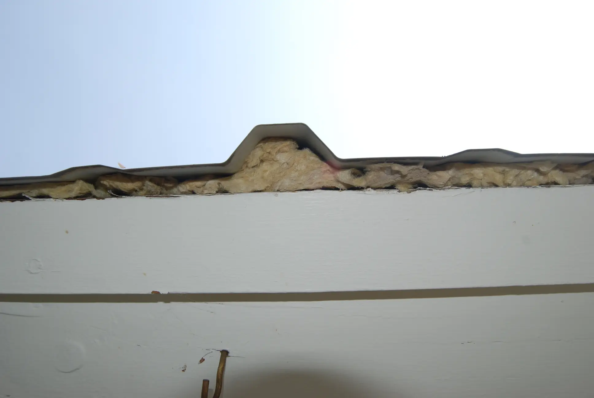 Metal roof with open ends and noncombustible mineral wool batt insulation to prevent ember and debris accumulation.