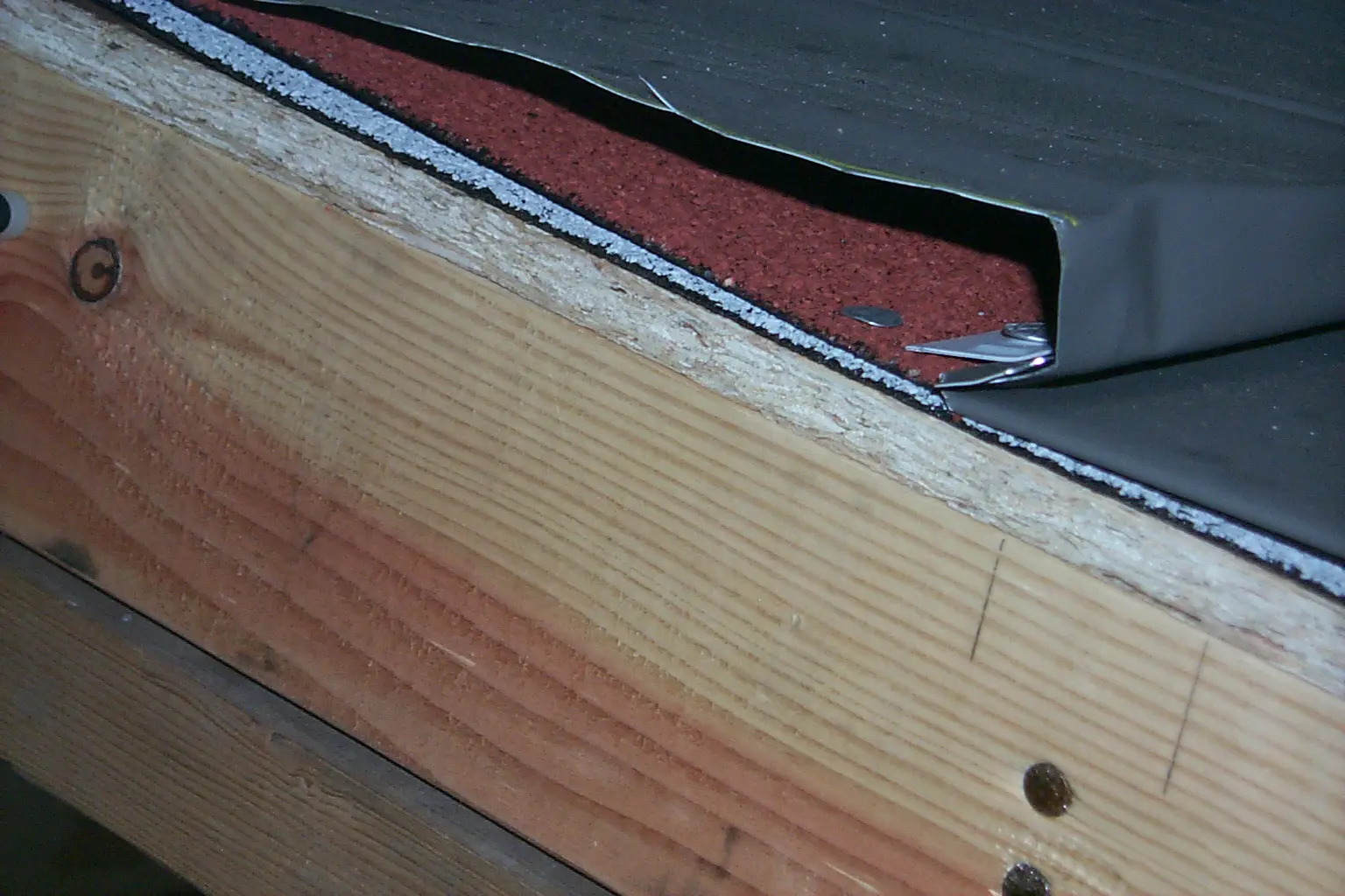Aluminum roof covering with an asphalt fiberglass composition roll roofing product used as an underlayment.  Note that this is a cutaway view of a specimen under evaluation in a laboratory environment.